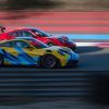 Deux Porsche 911 GT3 type 992, l'une rouge et l'une jaune, en pleine course côte à côte sur le circuit Paul Ricard.